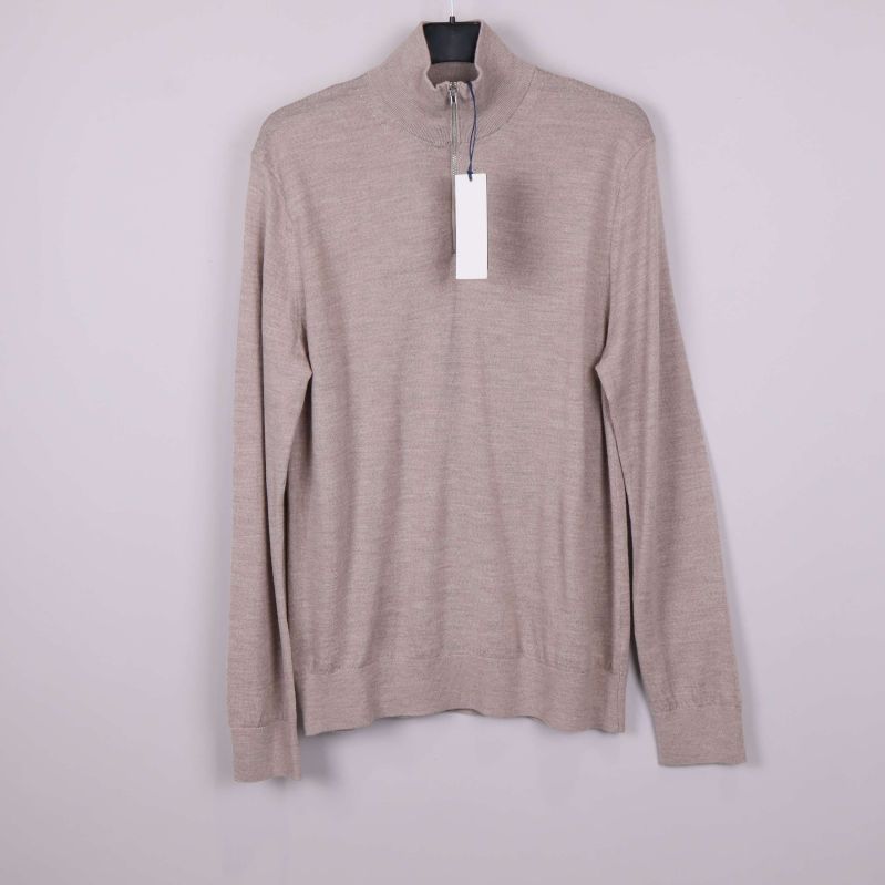 Beige tröja med halvzip upphängd mot ljus bakgrund
