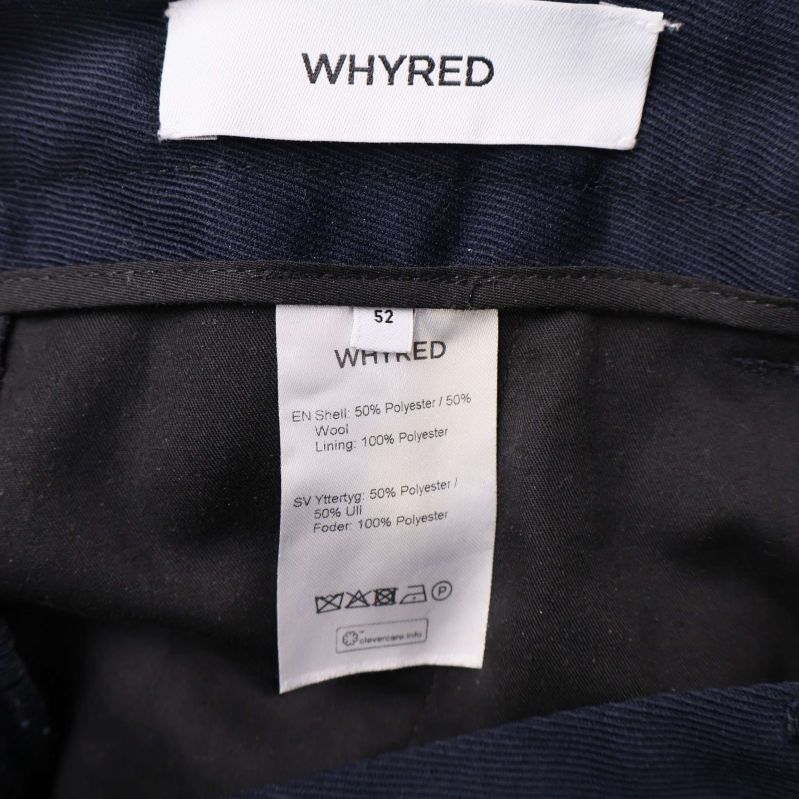 Närbild på Whyred-logga och materiallapp inuti kostymbyxa