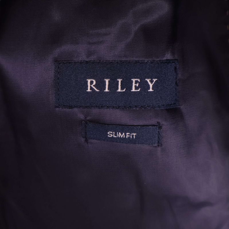 Närbild på RILEY-märkesetikett och slim fit-markering inuti kavajen