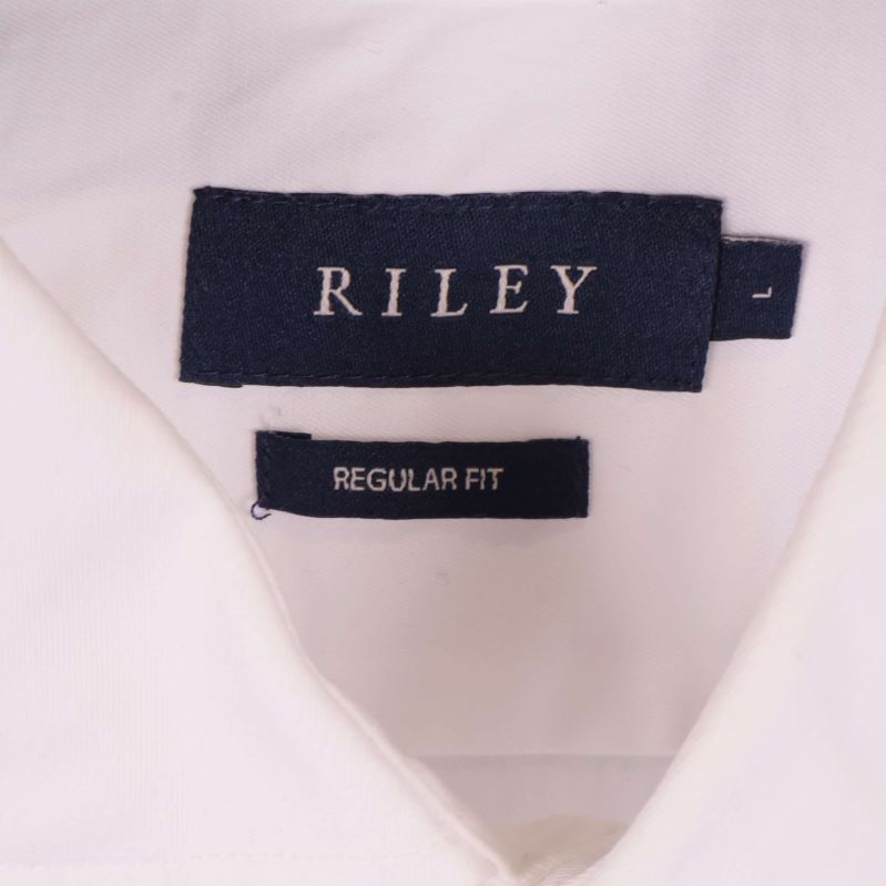 Närbild på Riley logotyp i nacken på vit skjorta