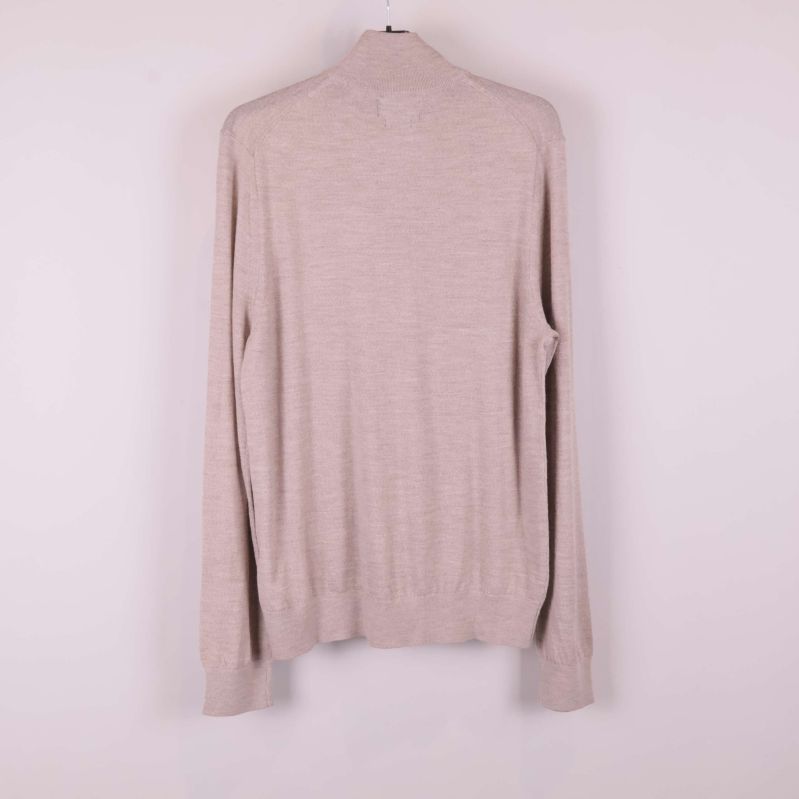 Beige stickad tröja sedd bakifrån på galge