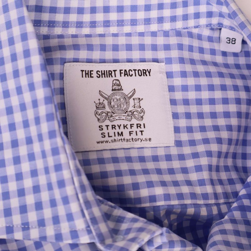 Närbild på logotyp och etikett The Shirt Factory