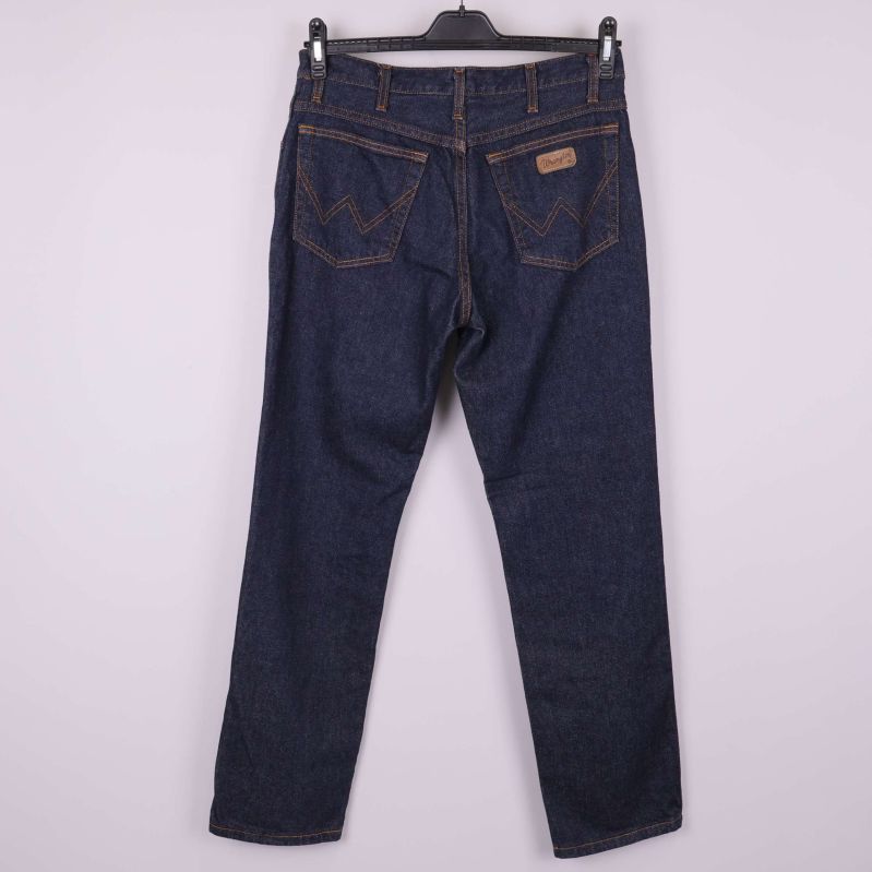 Baksida av mörkblå jeans med fickor och guldbroderi