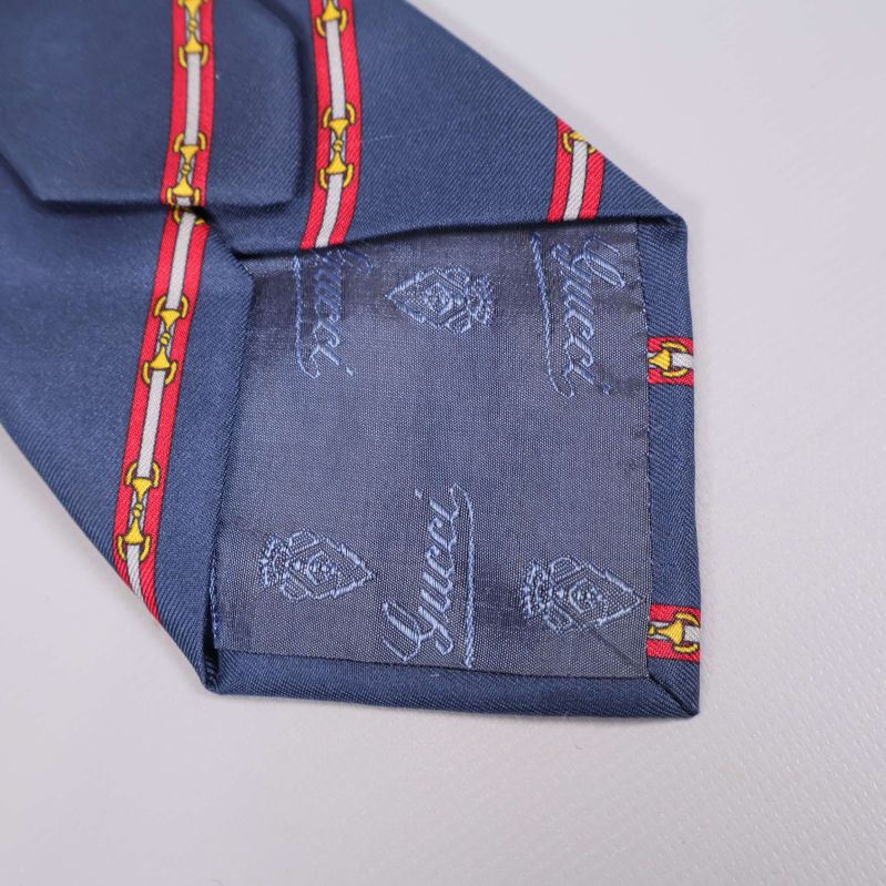 Närbild på slipsens spets med vävd Gucci-logo