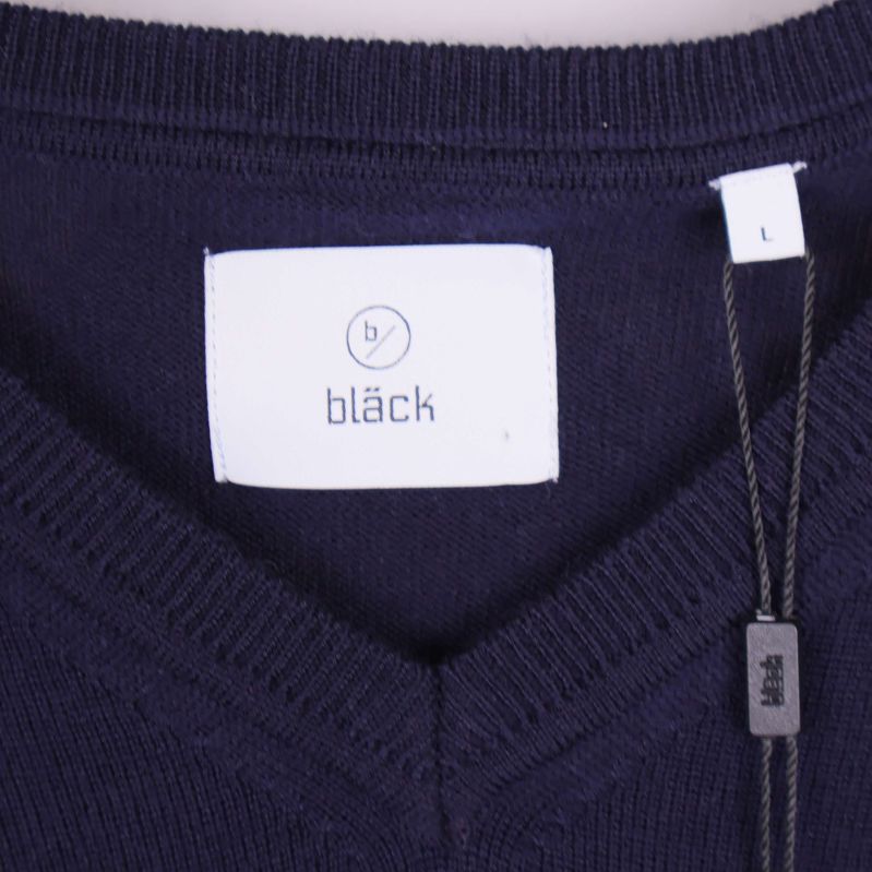 Närbild på etikett med bläck-logotyp framtill i nacken