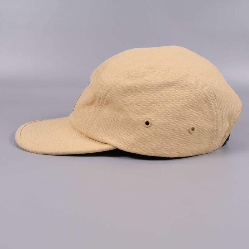 Beige keps sedd i profil med detaljerade sömmar och hål