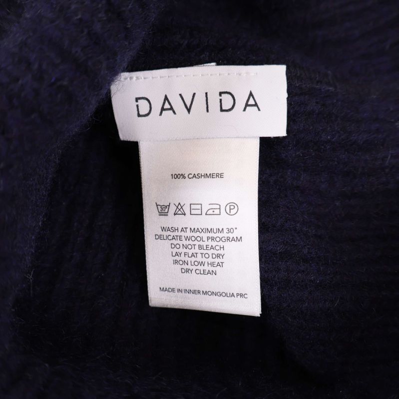Närbild på inneretikett som visar Davida och materialangivelsen 100% kashmir