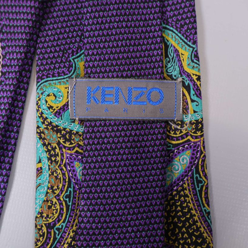 Närbild på Kenzo-logotypen i blått på slipsen