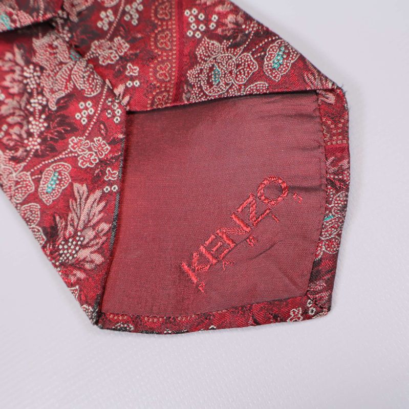 Närbild på spetsen av slips med broderad Kenzo-logga
