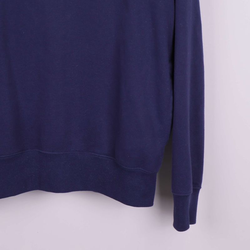 Närbild på nederkant och ärmslut av marinblå hoodie
