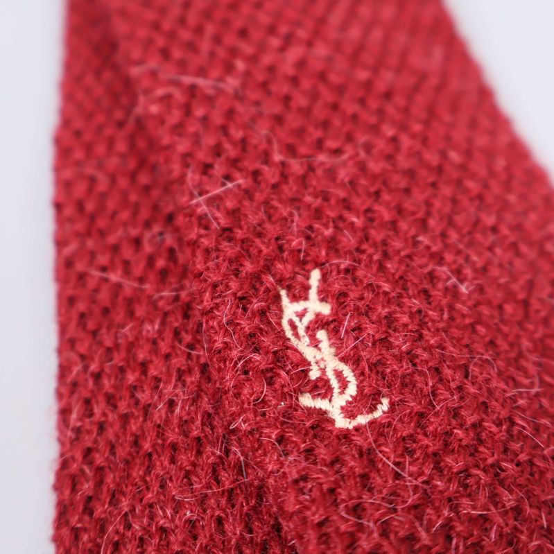 Närbild på YSL-logo broderad på röd stickad slips