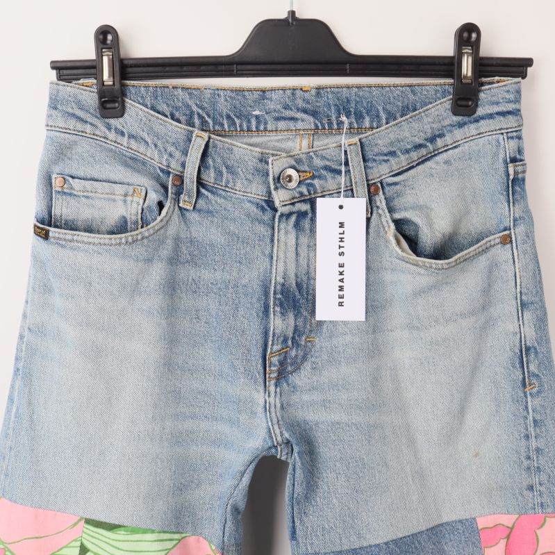 Framsida av jeans med närbild av fickor och knappförslutning
