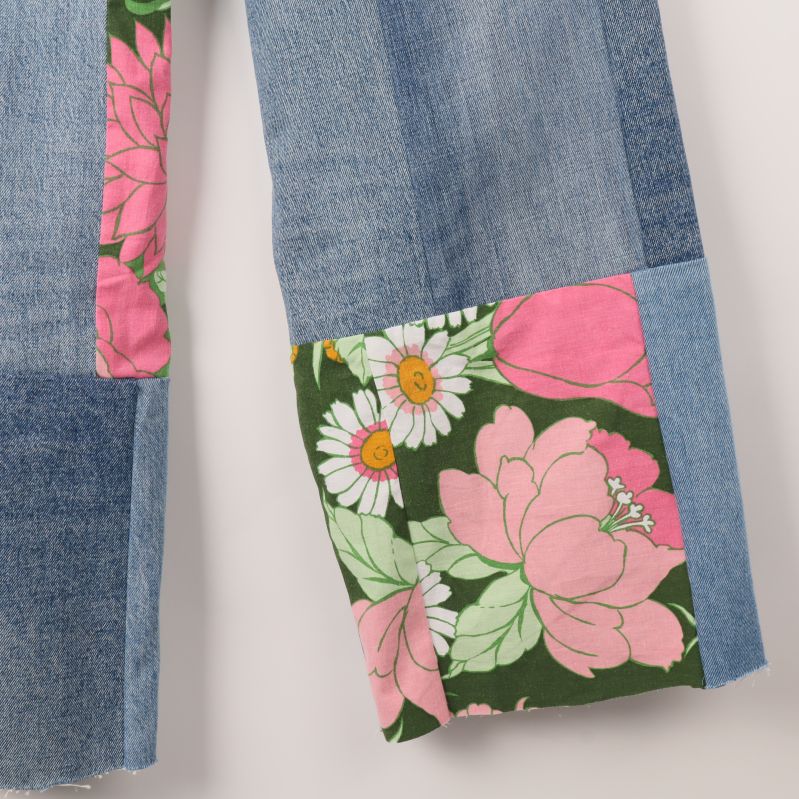 Närbild av blommig patchworkdetalj vid jeansbenets nederkant