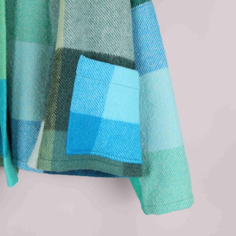 Närbild på jackans ficka och rutigt tyg