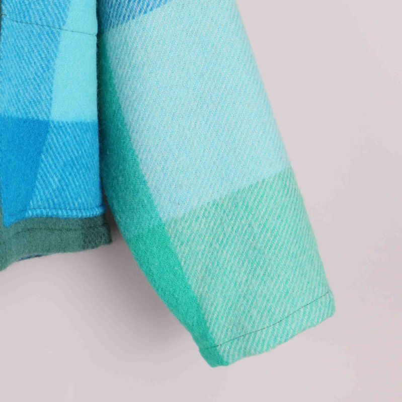 Närbild på jackärm med blågröna och ljusa rutor