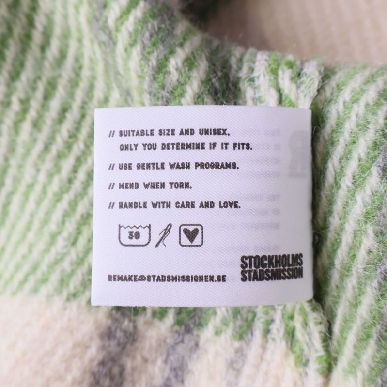 Tvättrådsetikett insydd i stickad grön- och cremefärgad cardigan