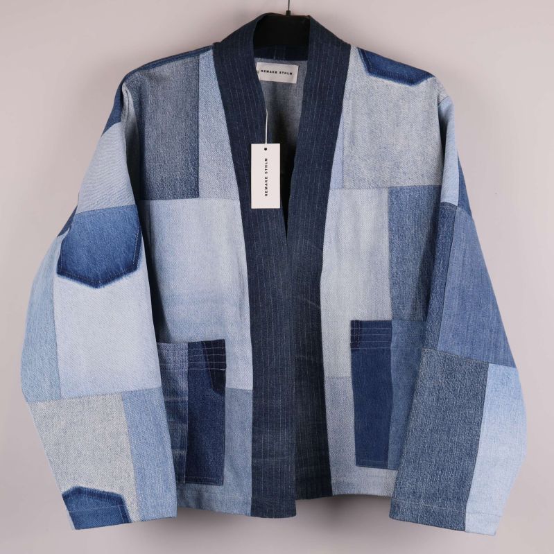 Patchwork denimjacka hänger mot ljus bakgrund