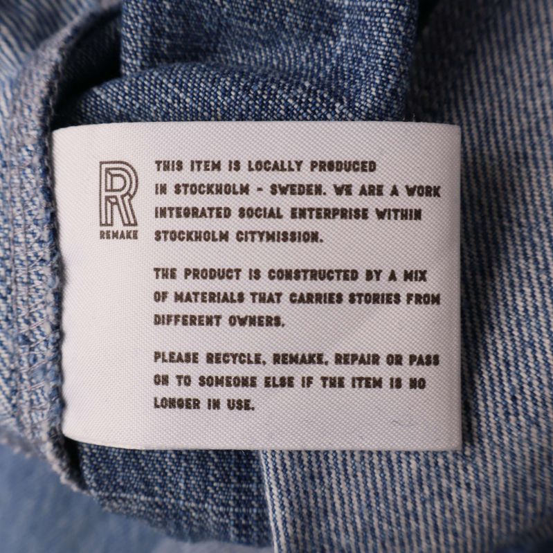 Informationslapp om producent och material på jeans