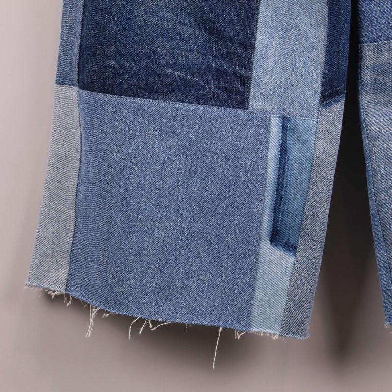 Närbild på fransig benslut nederkant av denimbyxa