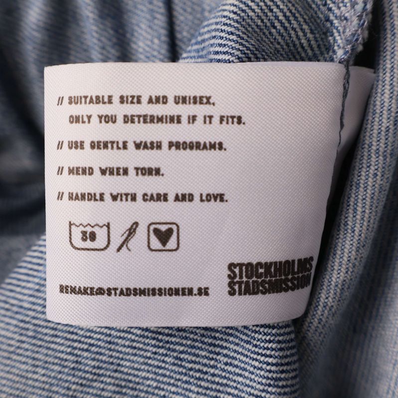 Tvättrådslapp och tvättsymboler på denimbyxa