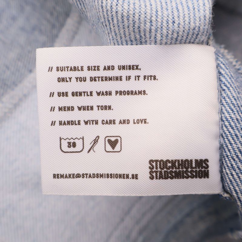 Tvättrådsetikett med symboler och engelsk text om skötsel