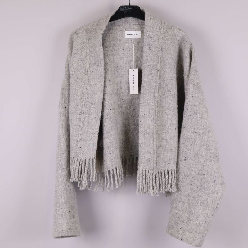 Ljusrå stickad jacka på galge med fransdetaljer framtill