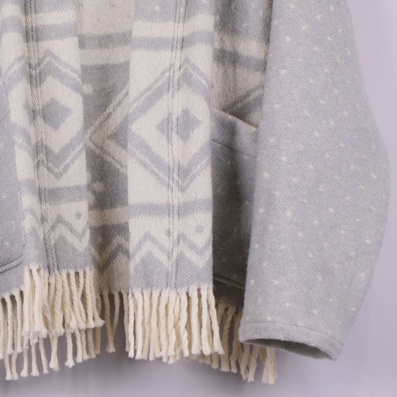 Närbild på nederkantens fransar och fickor på cardigan