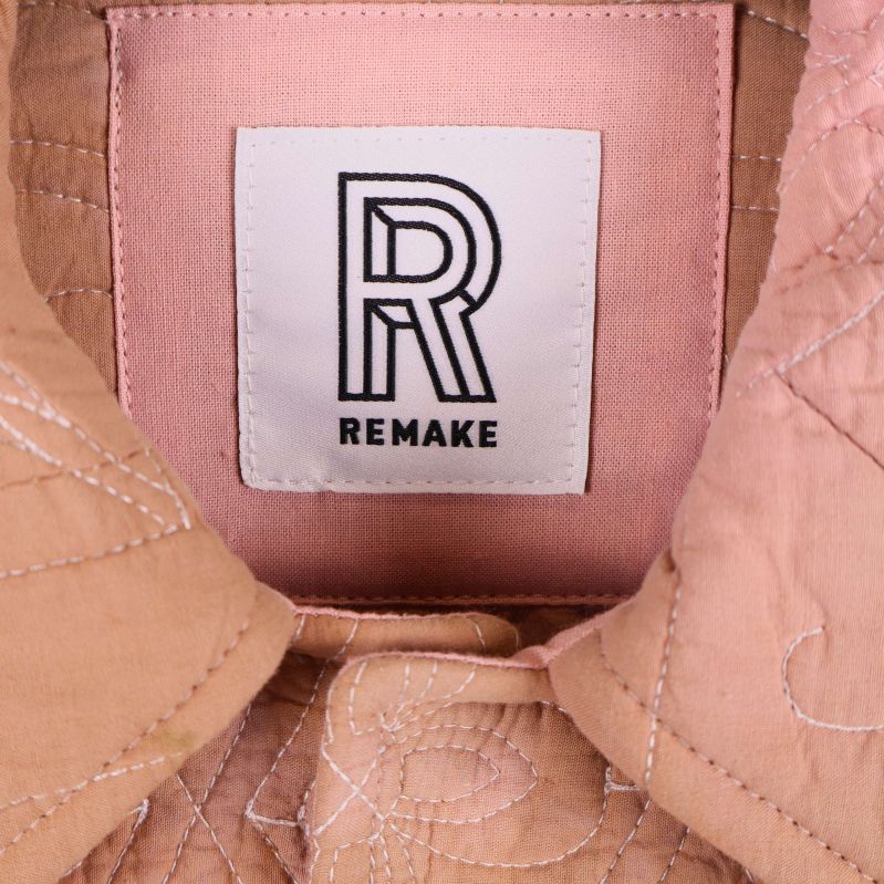 Närbild på Remake-logotyp i jackans krage