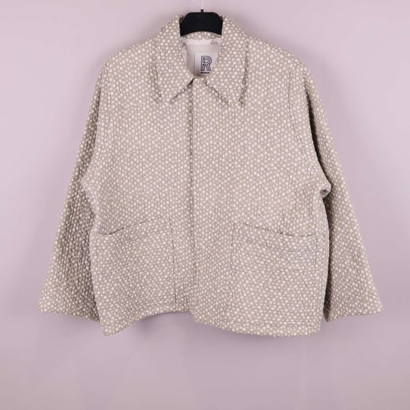 Framsida av prickig quiltad jacka på galge