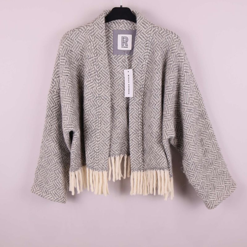 Kort jacka med mönster och fransar framtill hänger på galge