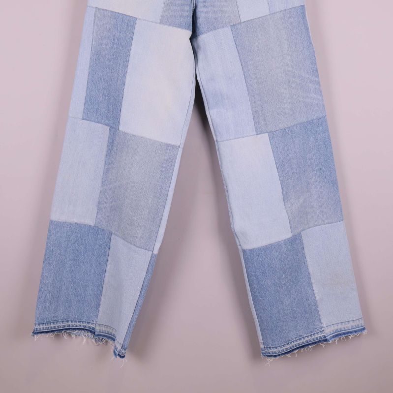 Jeansben med rå kant och olika denimlappar i närbild