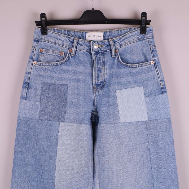 Närbild framtill på patchwork jeansens fickor och gylf