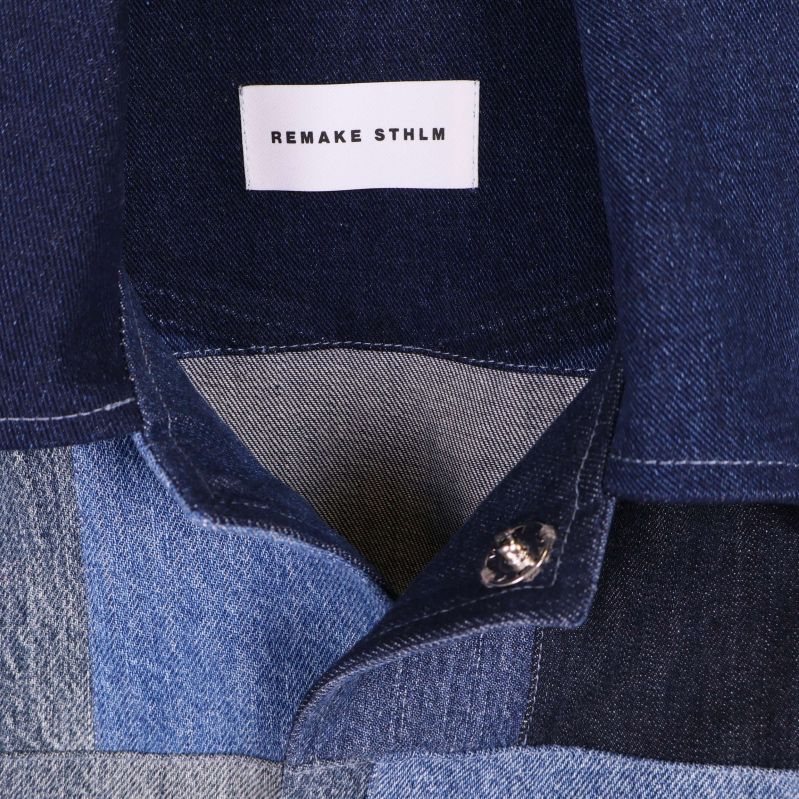 Närbild på krage och knäppning samt etikett Remake Sthlm