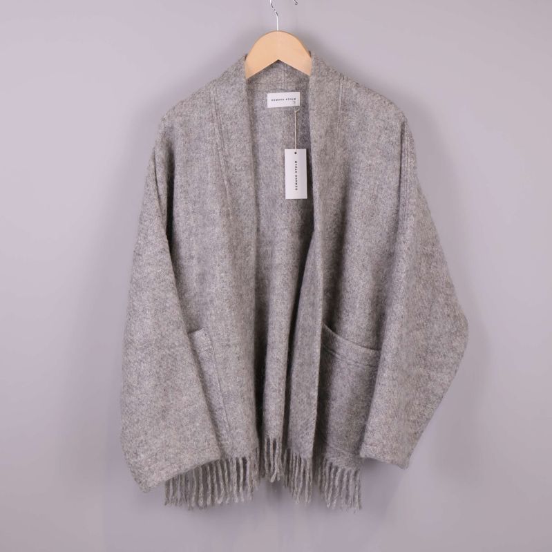 Grå stickad kimono med fransar hänger på galge