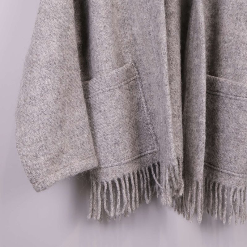 Närbild på fickor och fransar på grå stickad kimono