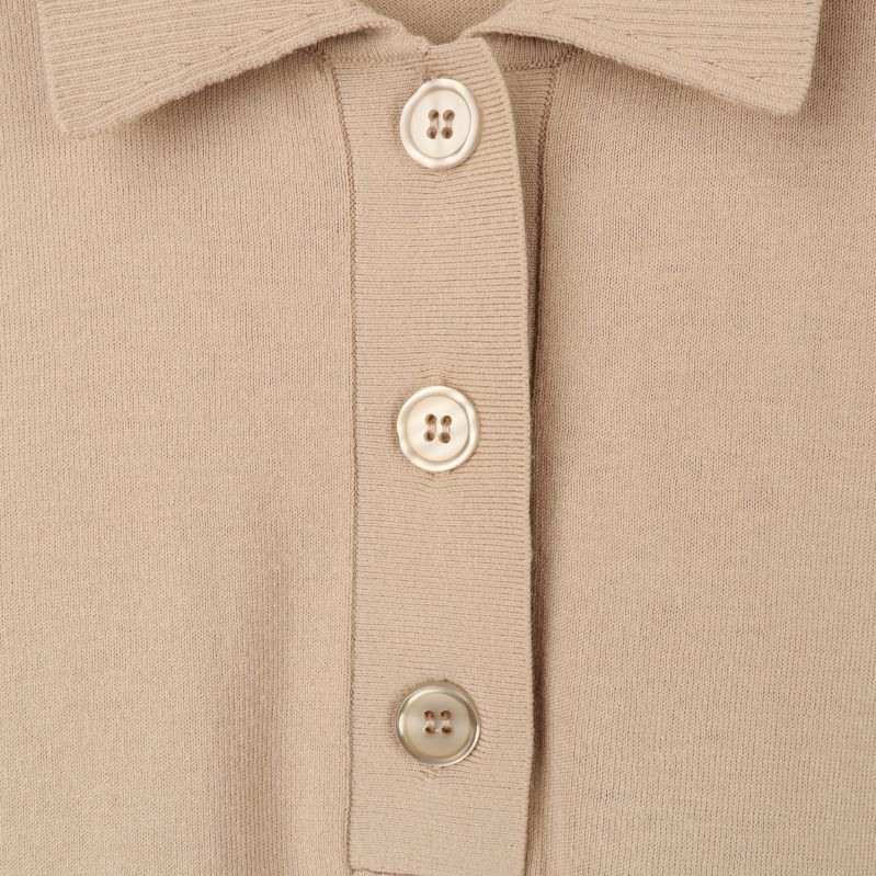 Närbild av knappar på beige polotröja