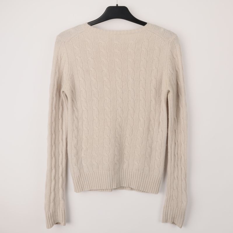 Baksidan av kabelstickad beige tröja