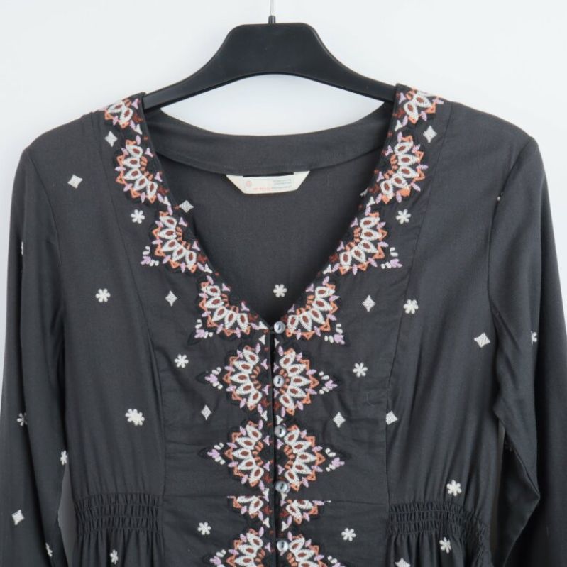 Närbild på broderade detaljer vid halsen