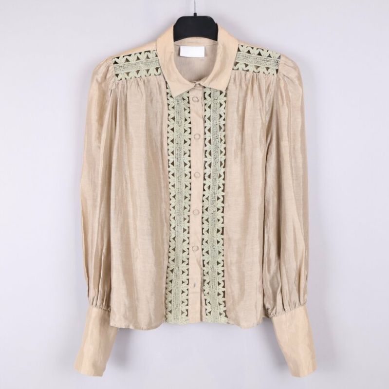 Framsidan av beige blus med spetsdetaljer