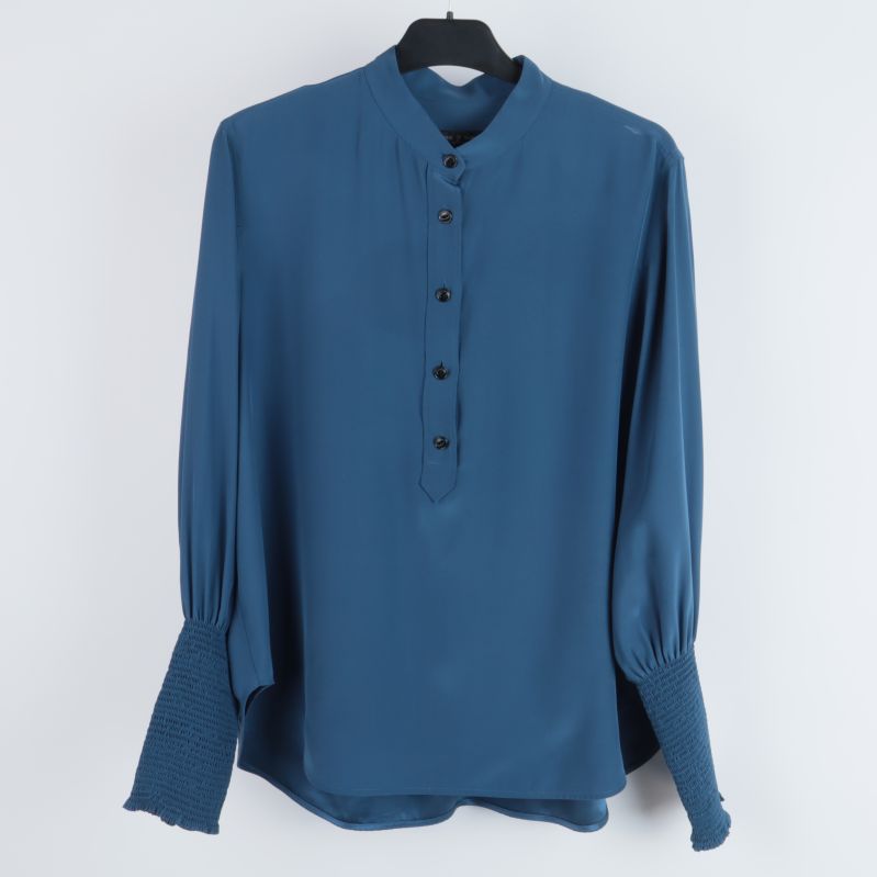 Framifrån sedd blå blus med krage och knappar