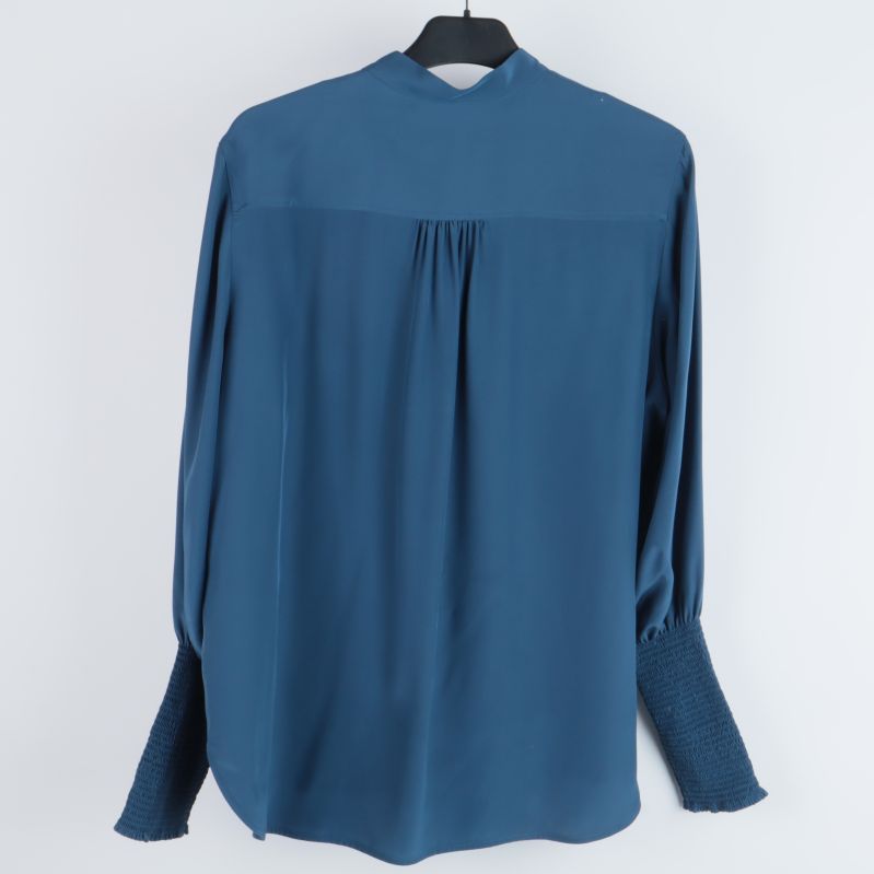 Baksidan av blå blus med veckdetaljer