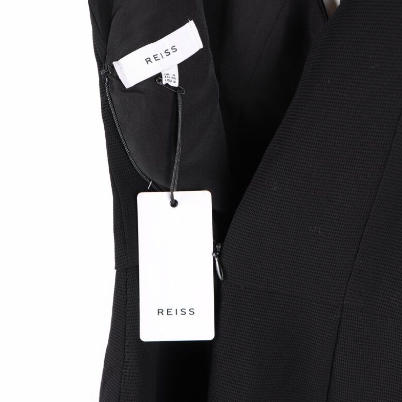 Vit etikett med Reiss-logotyp hängande från klänningen