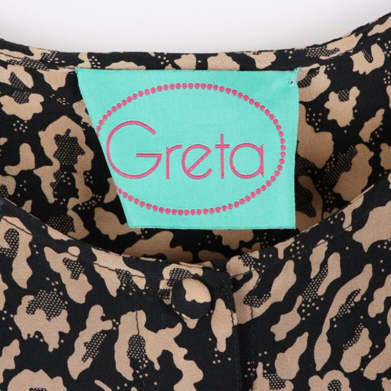 Närbild av Greta-logotypen på klänningen