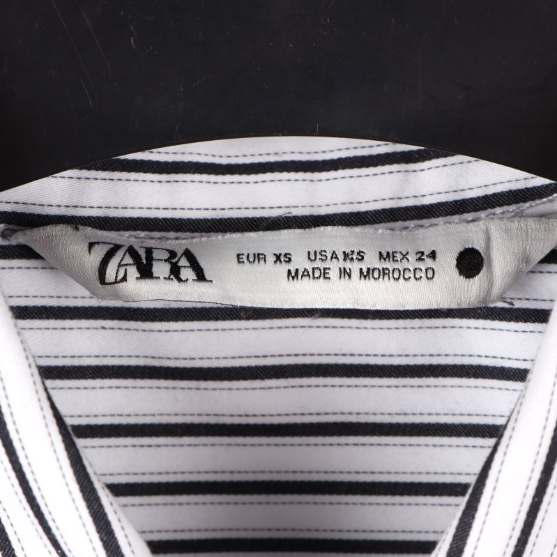 Närbild av ZARA-märket i skjortkragen