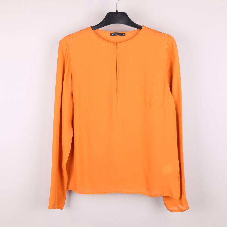 Framsida av orange blus på galge