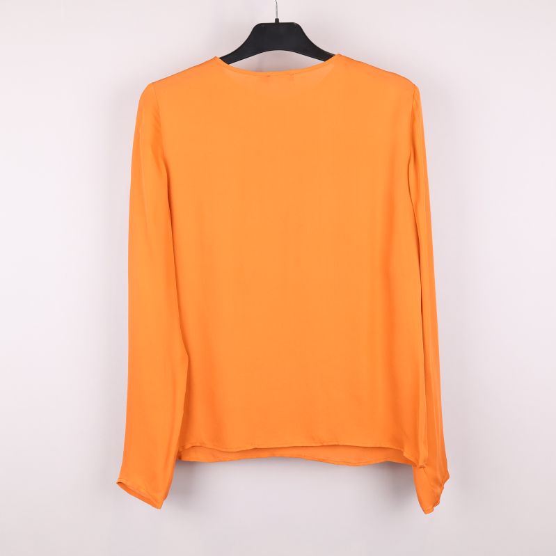 Baksida av orange blus på galge