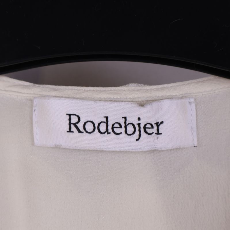Närbild på Rodebjer logotyp på blusen