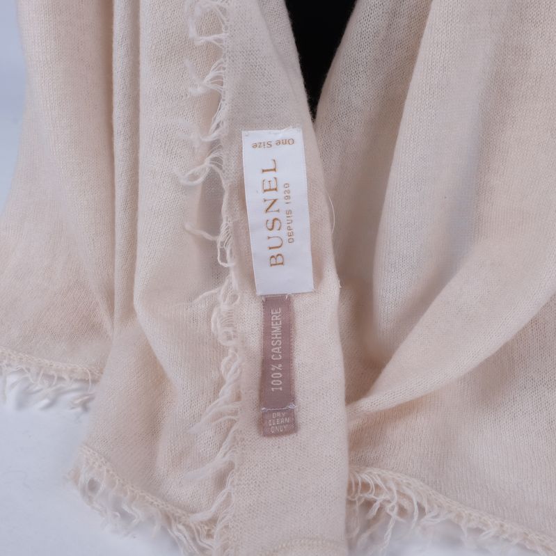 Närbild av Busnel märkestagg på beige halsduk
