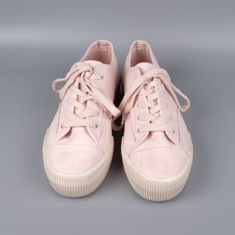 Sidan av ljusrosa sneakers med detaljsöm och platåsula