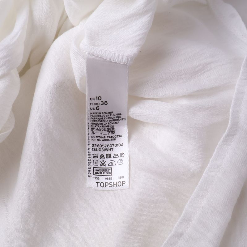 Storleksetikett på vit blus med materialinformation